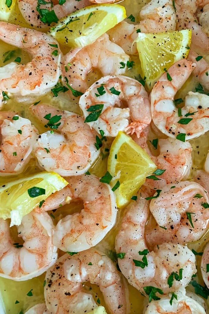 close up shot of oven baked shrimp with sliced lemons in a lage baking dish