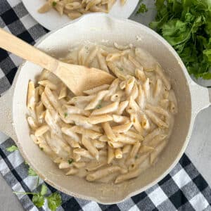 creamy cottage cheese alfredo sauce served over noodles. Pictured in a large skillet with a serving plate in the top left corner