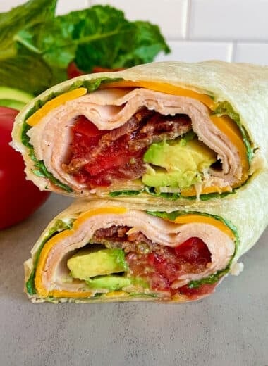 turkey club wrap made and cut in half, stacked on top of each other to show the inside of the wrap