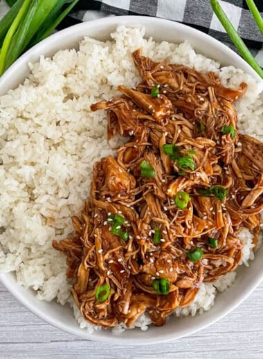Easy slow cooker honey garlic chicken served over a bed of white rice topped with diced green onions