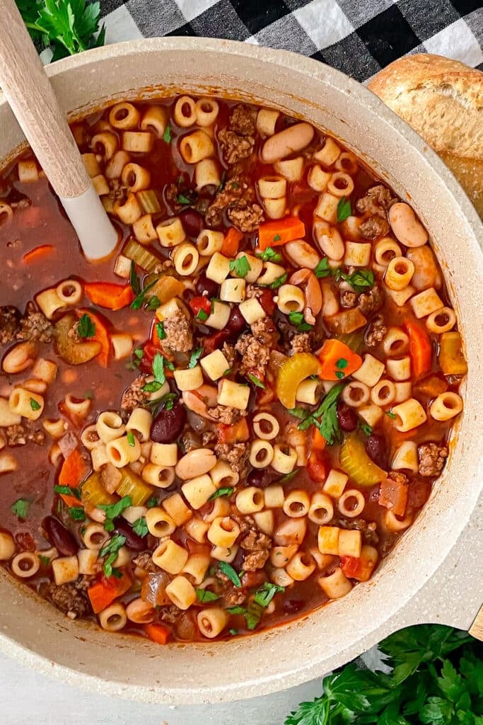 olive garden pasta e fagioli soup in a large pot with a serving spoon placed inside.