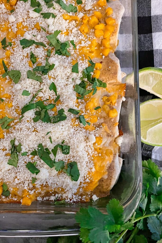 pan of Mexican street corn enchiladas cooked and topped with cojita cheese, cilantro, and Tajin seasoning