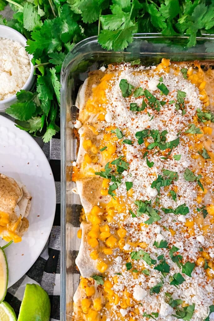 pan of Mexican street corn enchiladas cooked and topped with cojita cheese, cilantro, and Tajin seasoning