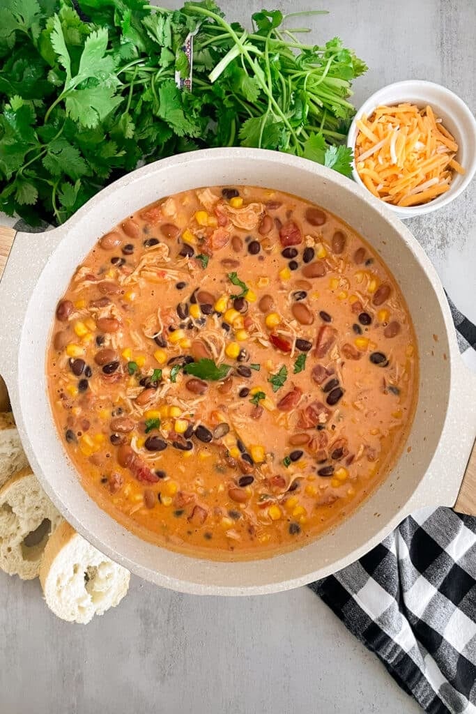 large pot of creamy taco soup with a side of shredded cheese and cilantro