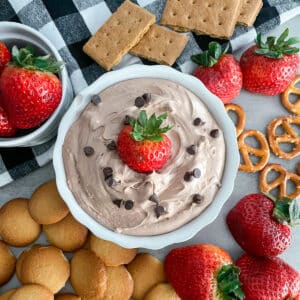 creamy Nutella fruit dip in a serving bowl surrounded by strawberries, cookies, and graham crackers