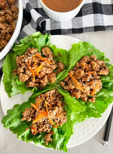 copycat P.F. changs lettuce on a white plate for serving. Peanut sauce and skillet with turkey filling on the side