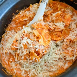 slow cooker Italian chicken pasta in a slow cooker with a large spoon taking a portion out of the crock pot