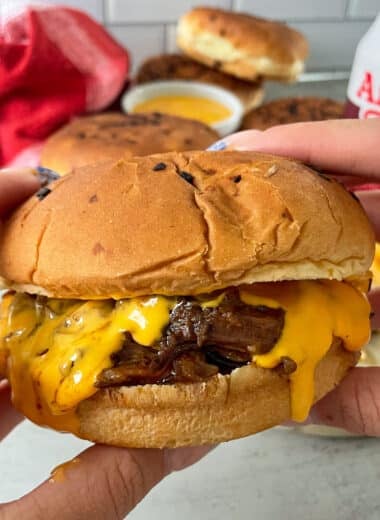close up photo of Arby's beef and cheddar held in a hand ready to be eaten.