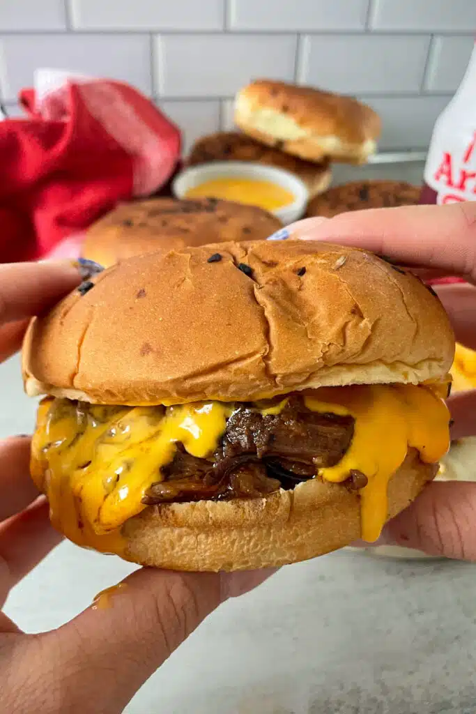 close up photo of Arby's beef and cheddar held in a hand ready to be eaten. 