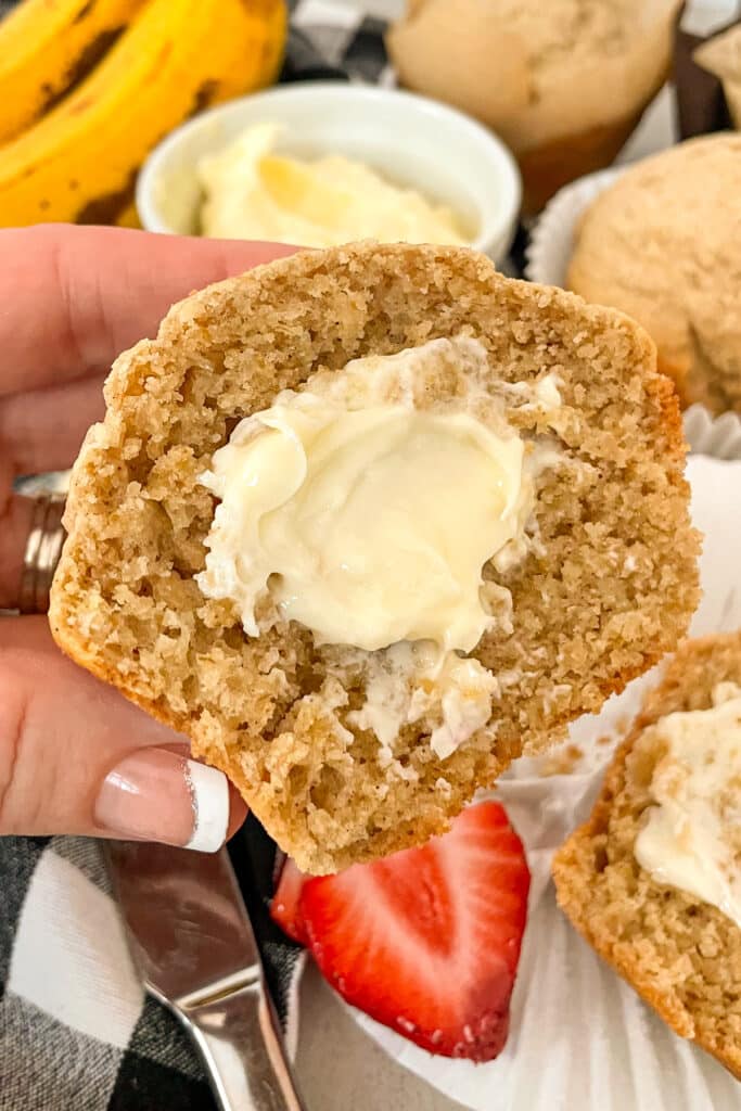 Close up shot of a Bran muffin that has been cut in half to show texture and smeared with softened butter.