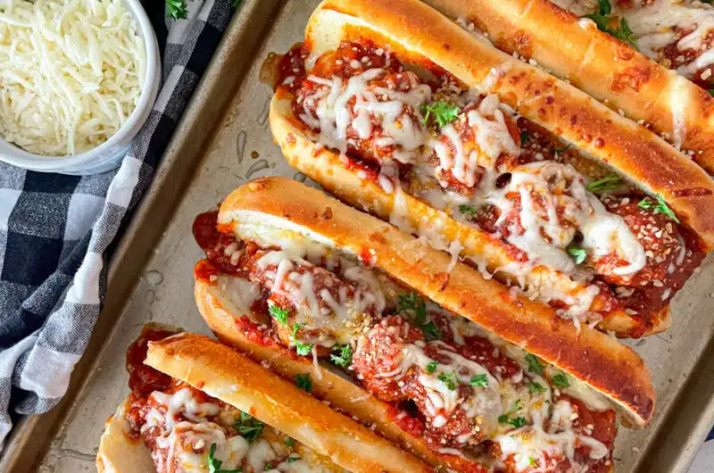 pan of 5 crock pot Italian meatballs subs ready to serve. shredded cheese and parsley in the upper left picture.