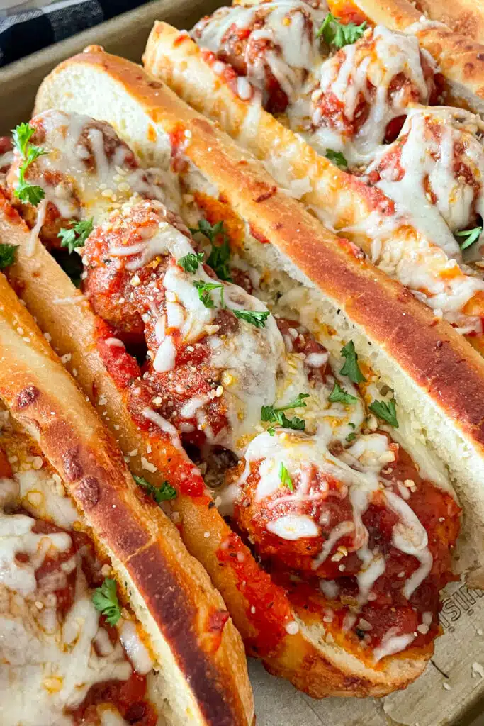 close up shot of meatball sub topped with mozzarella cheese and parsley