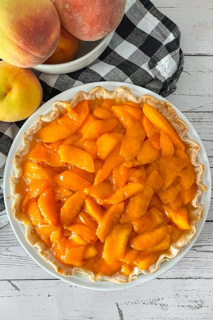 Fresh peaches and cream pie ready to be served. Fresh peaches on the side.