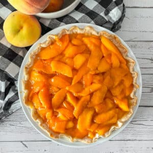 Fresh peaches and cream pie ready to be served. Fresh peaches on the side.