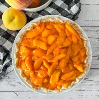 Fresh peaches and cream pie ready to be served. Fresh peaches on the side.