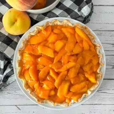 Fresh peaches and cream pie ready to be served. Fresh peaches on the side.