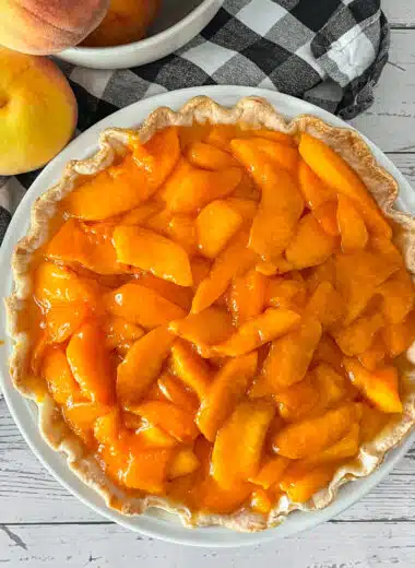 Fresh peaches and cream pie ready to be served. Fresh peaches on the side.