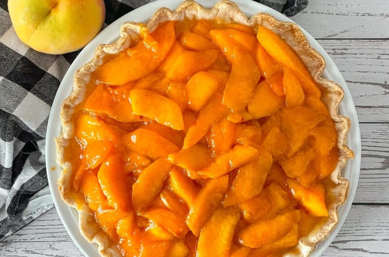 Fresh peaches and cream pie ready to be served. Fresh peaches on the side.
