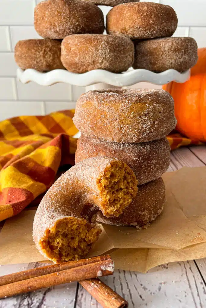 دونات اليقطين محلية الصنع جاهزة للتقديم. تُظهر الصورة قطعة دونات مقطوعة إلى نصفين لإظهار نسيج الدونات. 