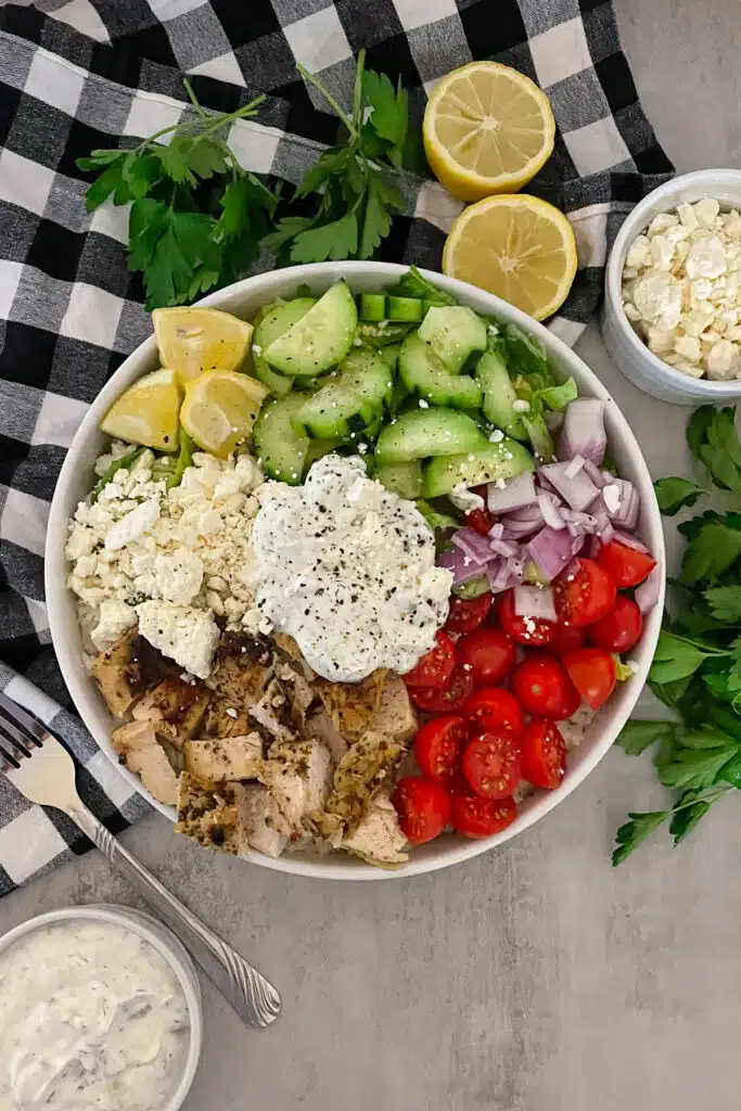 Healthy Greek Chicken bowl with tzatziki ready to serve with a side of feta cheese and lemons