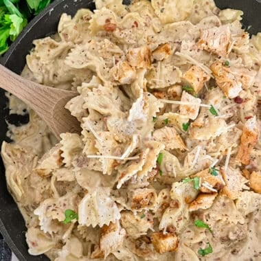 Skillet chicken bacon ranch pasta ready to serve with a side of bacon crumbles, parmesan cheese, and fresh basil.