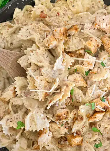 Skillet chicken bacon ranch pasta ready to serve with a side of bacon crumbles, parmesan cheese, and fresh basil.