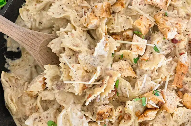 Skillet chicken bacon ranch pasta ready to serve with a side of bacon crumbles, parmesan cheese, and fresh basil.