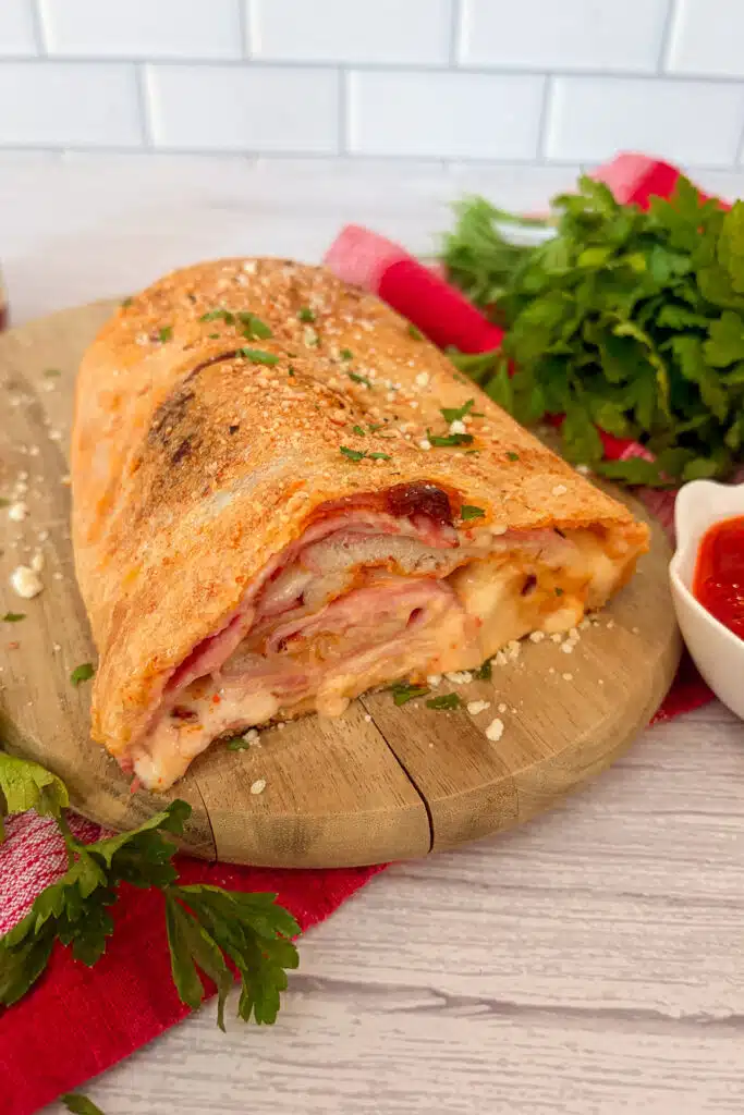 ham and cheese stromboli cut in half ready to serve with pizza sauce