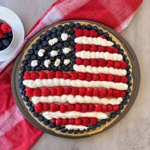 patriotic fruit pizza with a cup full of berries for serving.