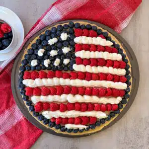patriotic fruit pizza with a cup full of berries for serving.