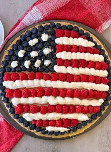 patriotic fruit pizza with a cup full of berries for serving.