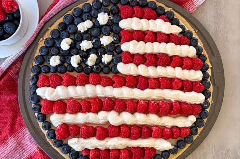 patriotic fruit pizza with a cup full of berries for serving.