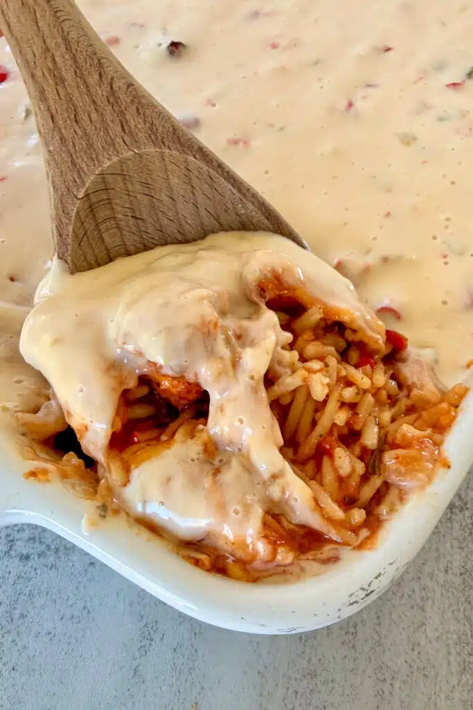 Creamy queso chicken and rice that is being spooned out of the casserole dish for serving.