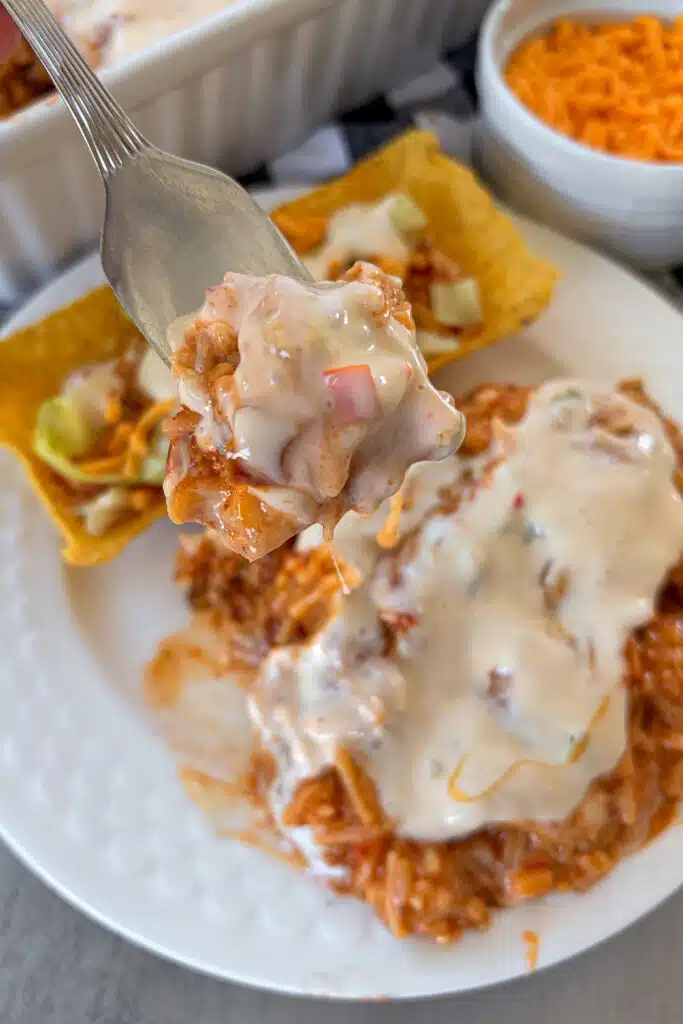 Queso chicken and rice on a serving plate with cheese for serving. The photo shows an up close look at a bite on a fork.