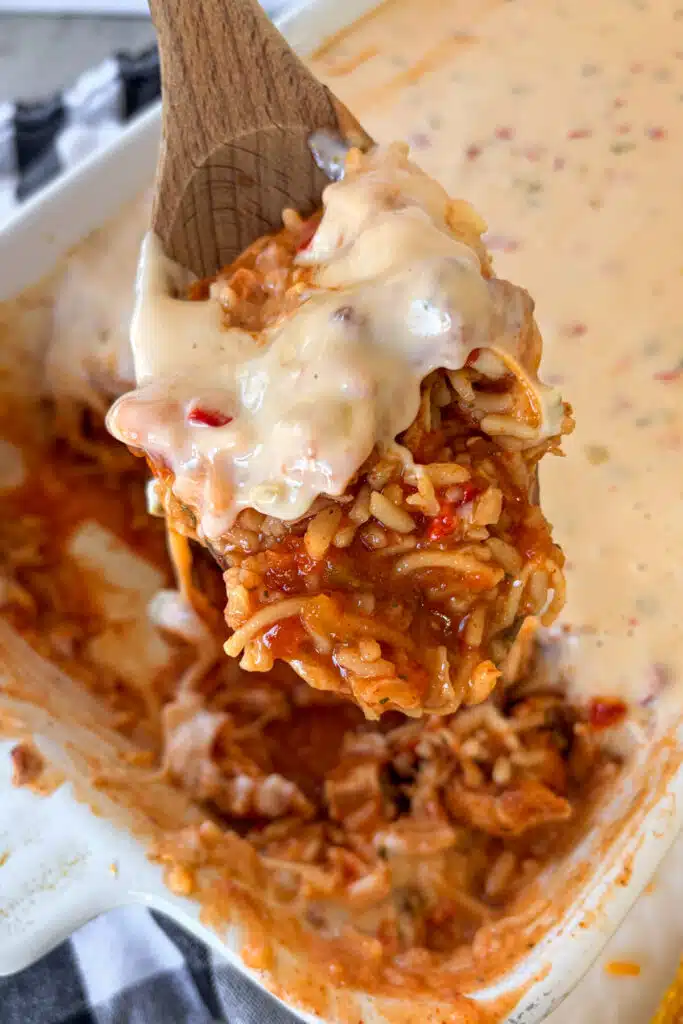Creamy queso chicken and rice that is being spooned out of the casserole dish for serving.